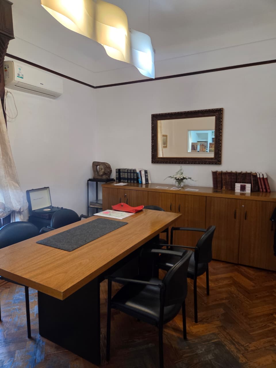 Detalle del escritorio del estudio con biblioteca jurídica y mobiliario clásico de madera.